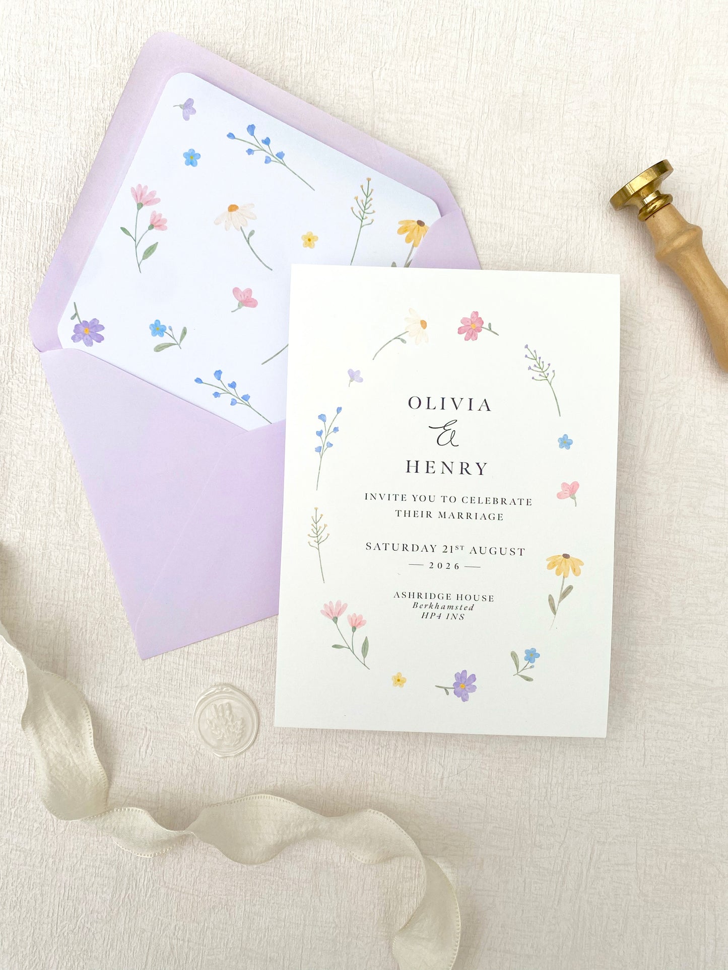 Wildflower wedding invitation card with floral design on a matching envelope, ribbon, and sealing wax.