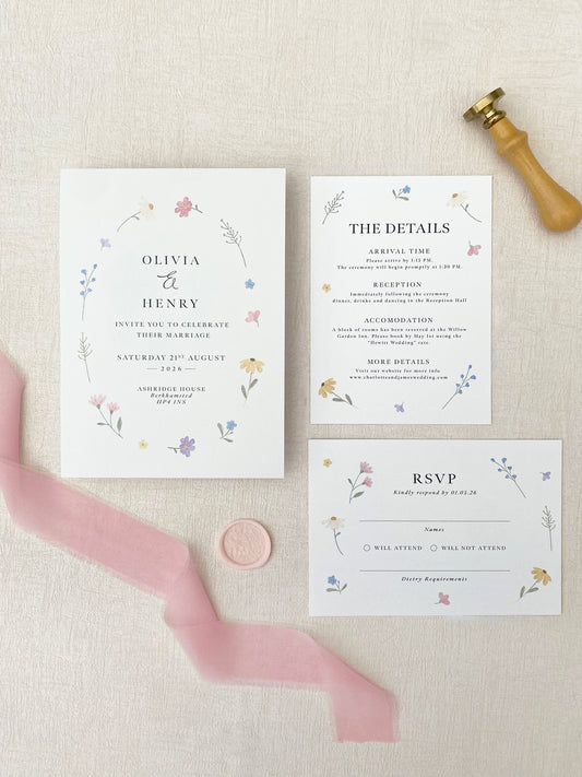 Set of wedding invitations with floral designs on a textured surface.