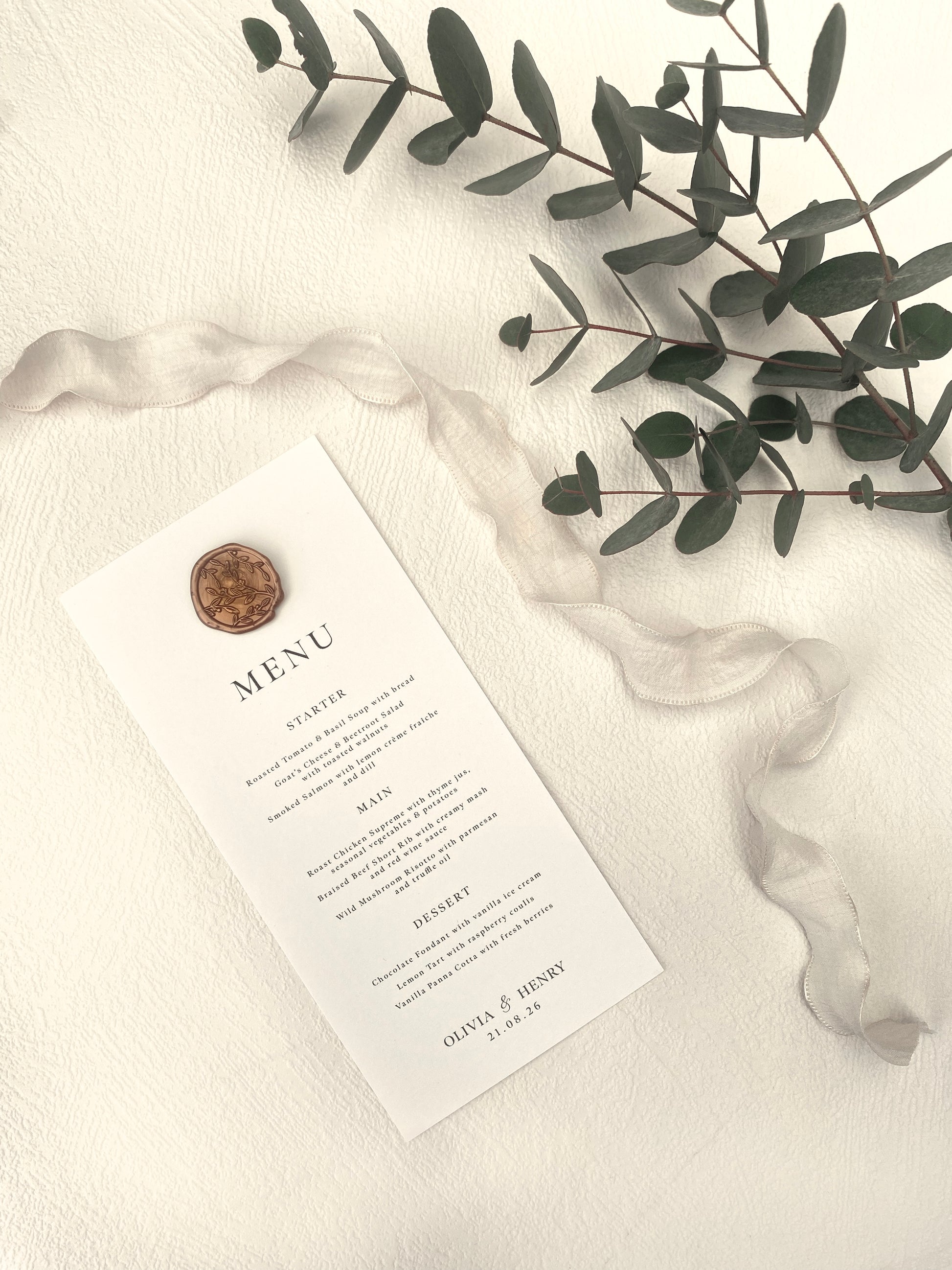Wedding menu card with a seal, ribbon, and eucalyptus leaves on a white background